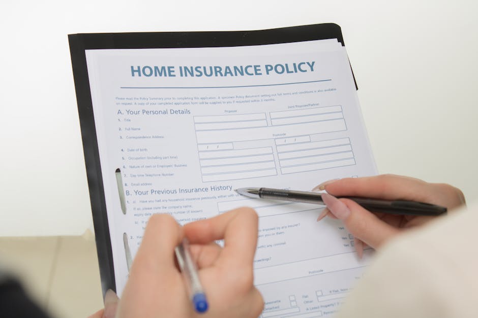A person holding a black clipboard containing a home insurance policy document titled 'HOME INSURANCE POLICY' with sections for personal details and previous insurance history. The individual is using a silver pen to fill out the form, resting their hands on a light-colored surface. The document is inside a residential property, with natural lighting illuminating the scene. This image illustrates the preparation and planning involved in home relocation, such as ensuring proper insurance coverage during a move. It relates to house removals and furniture transport services provided by Man With a Van Pimlico, highlighting the importance of liability and insurance considerations during the packing and moving process.